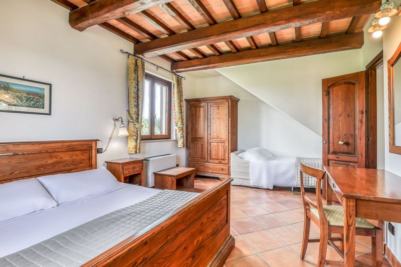 Camera con letto matrimoniale e un letto singolo, travi a vista e pavimento in cotto