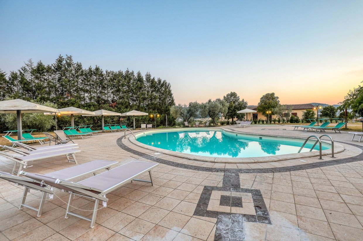 La piscina all'aperto al tramonto, con i lettini e gli ombrelloni chiusi