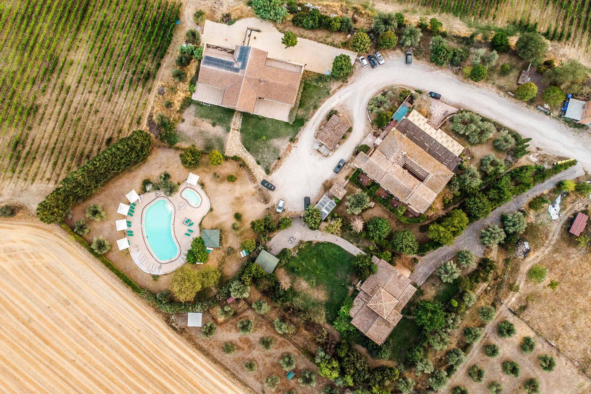 Veduta dall'alto dei casali, della piscina e del viale tra i campi e i vigneti